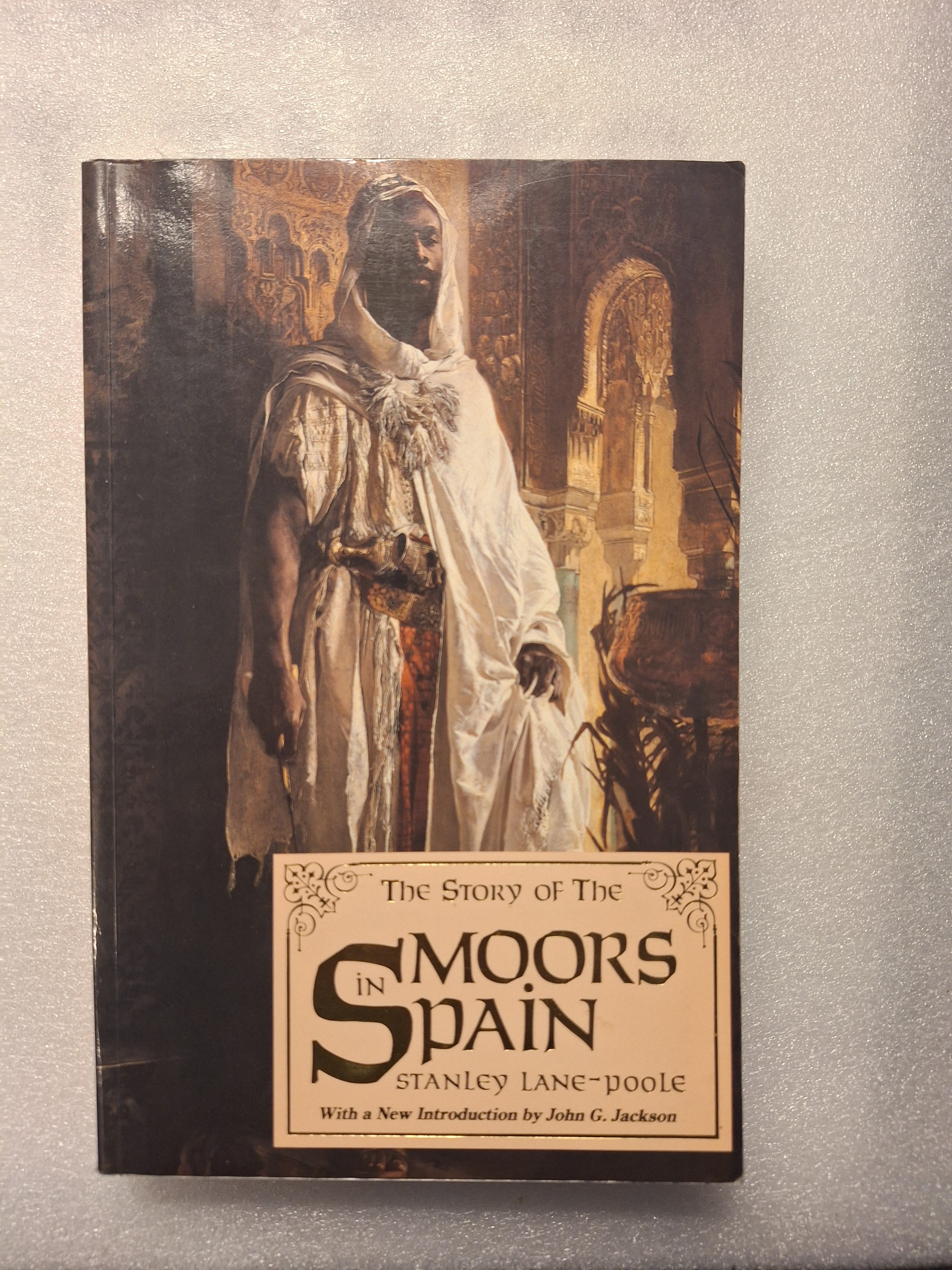 A book titled 'The Story of The Moors in Spain' by Stanley Lane-Poole, featuring a historical illustration of a Moorish man in traditional attire.